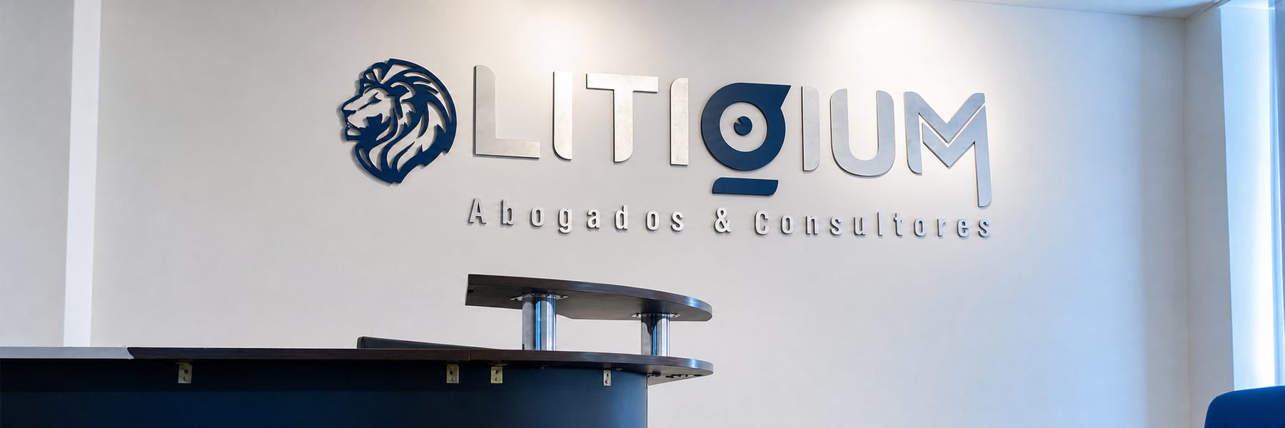 Recepción de Litigium Abogados & Consultores en Riobamba, con el logotipo del estudio en la pared